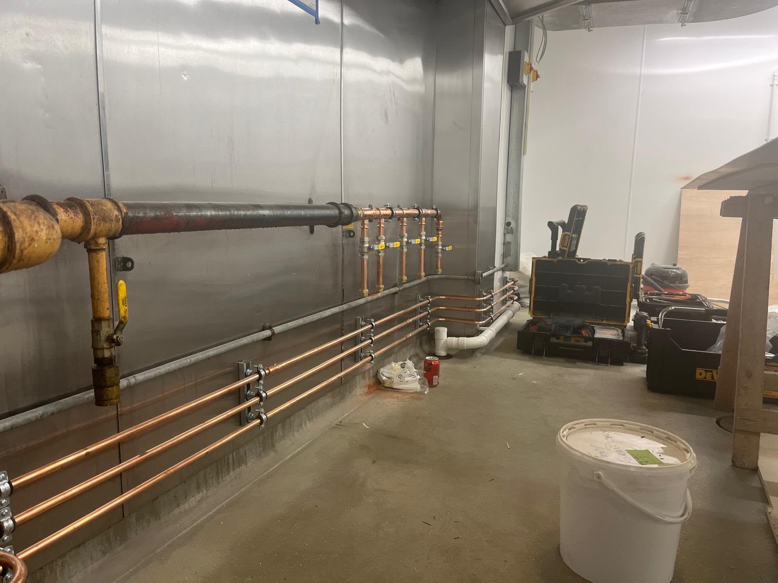 Commercial plant room with clipped horizontal copper pipe runs and an isolation valve manifold