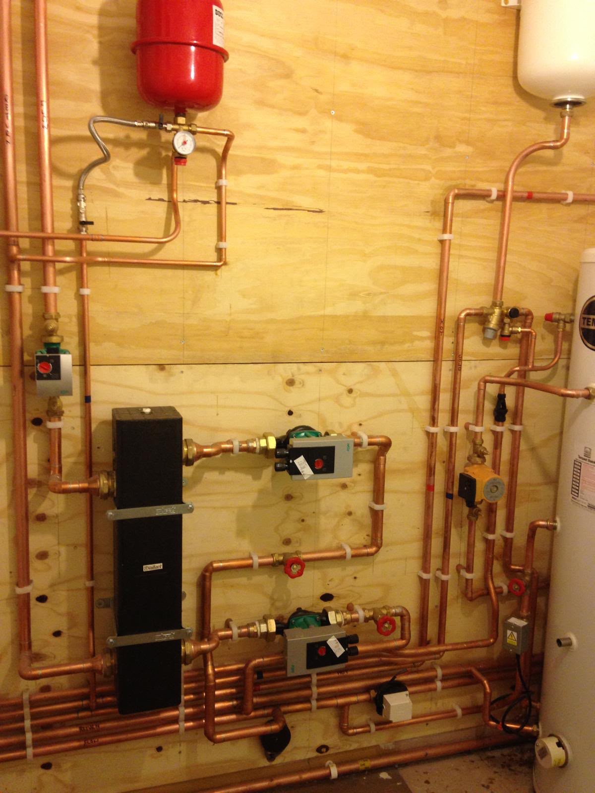 Vaillant low loss header with expansion vessels, pumps, wiring centres and neat copper pipework on a plant room wall